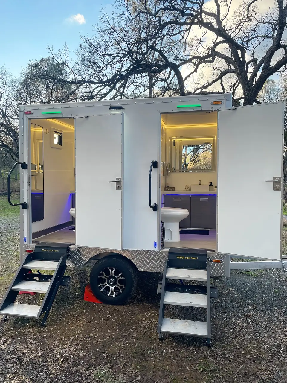 Two-stall restroom trailer with both doors open and lit steps