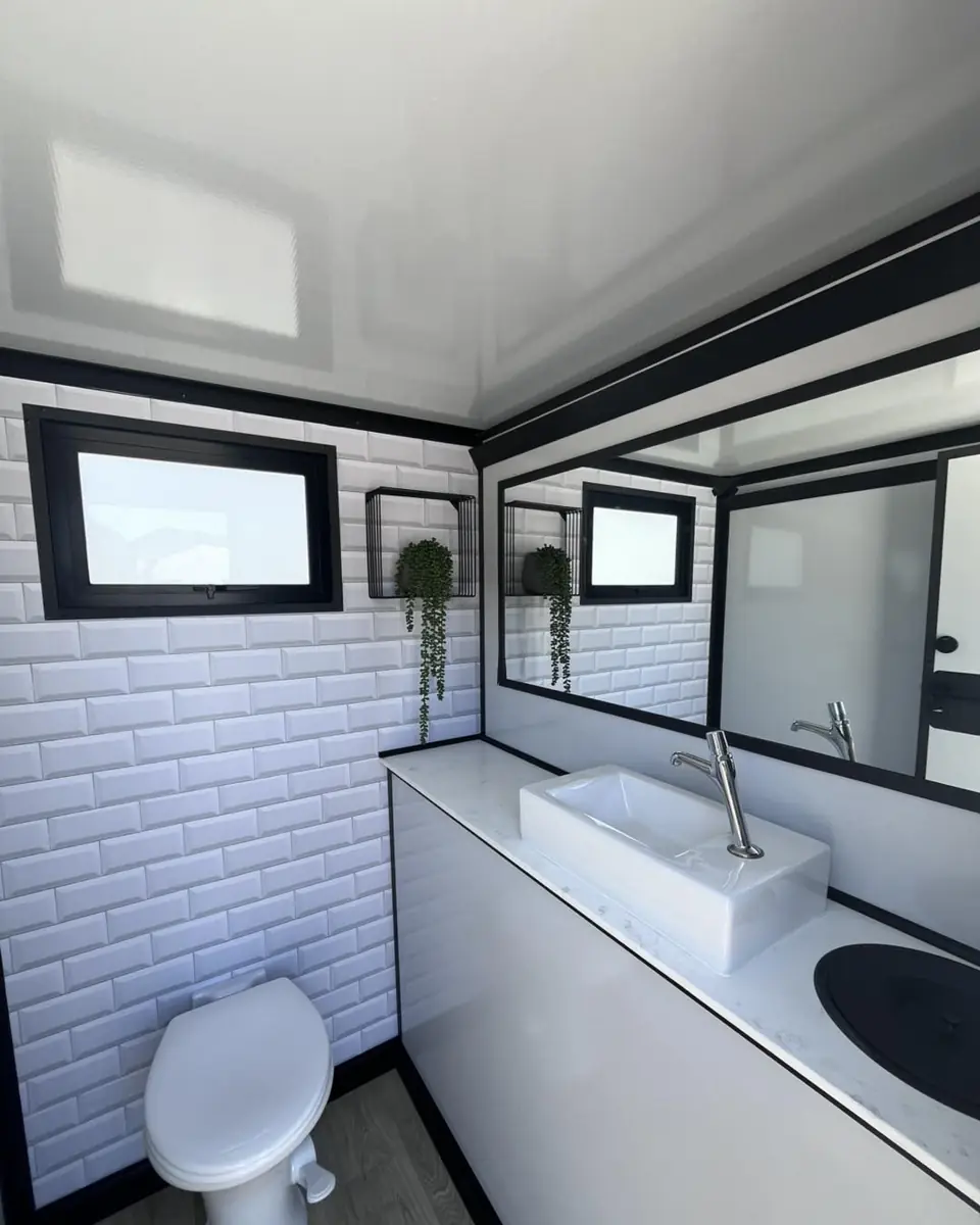 Restroom trailer interior with white tile wall, vanity sink and mirror